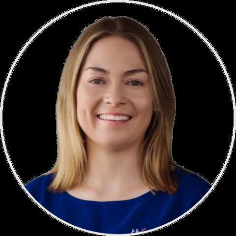 Professional headshot of a smiling woman with shoulder-length brown hair wearing a dark blue shirt against a black background
